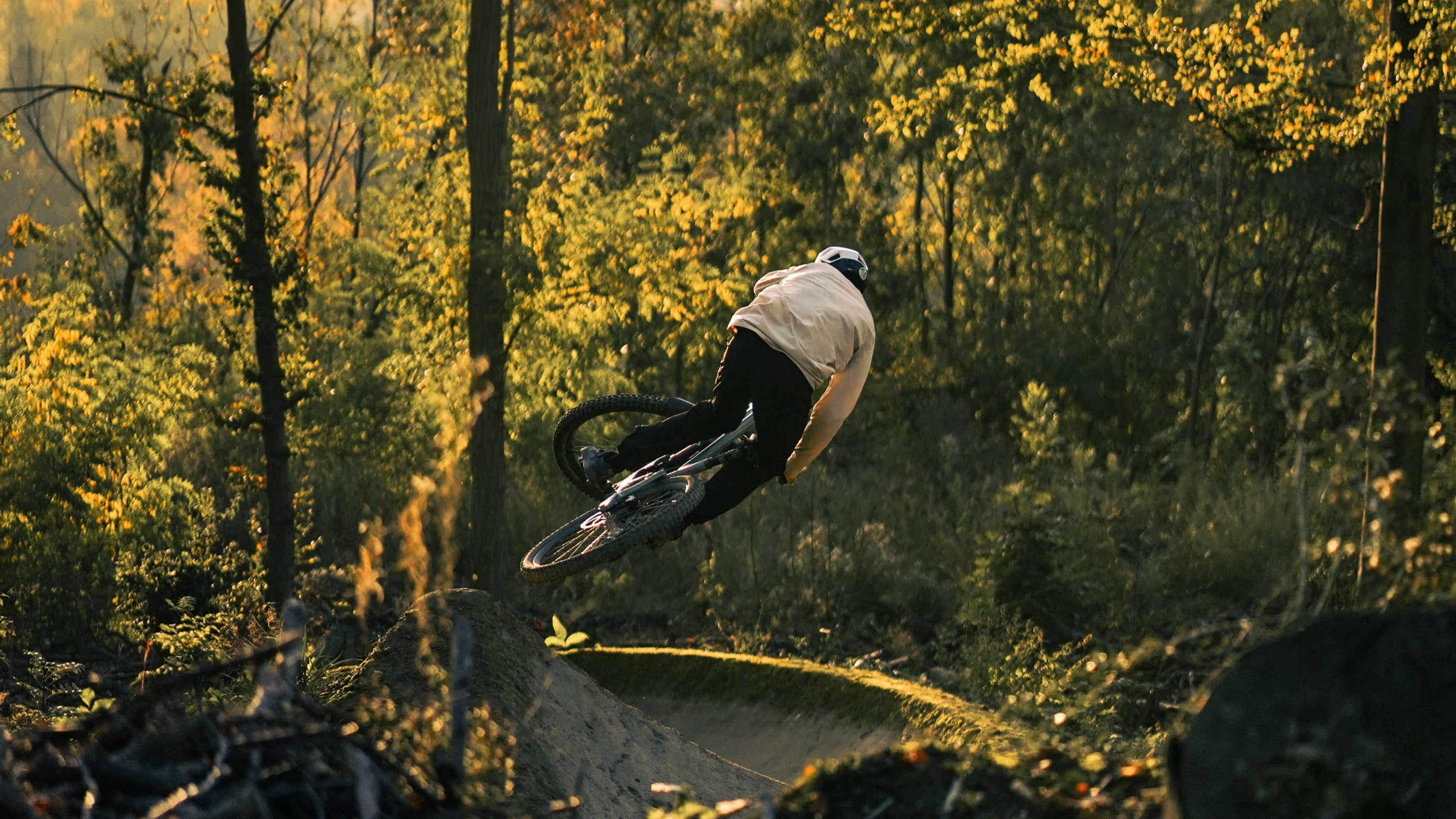 Image shows a bike rider on a Forbidden Druid jumping during sunset in the forest.